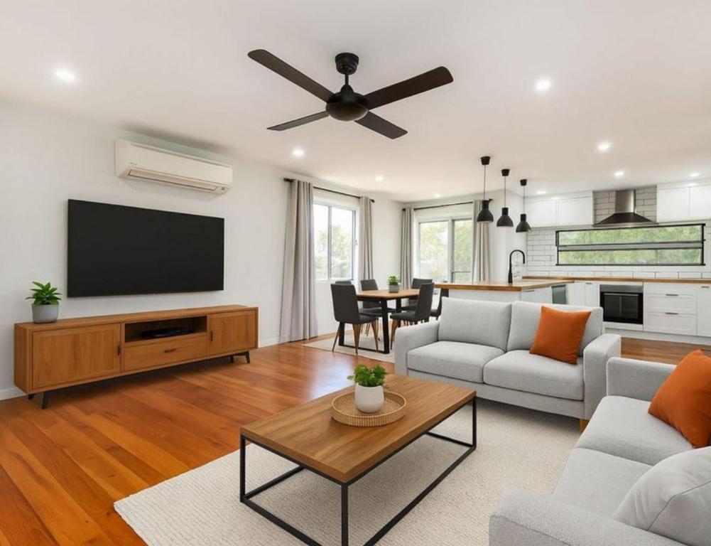 a living room with a flat screen tv and a table at Patricks Road Ferny Hills in Ferny Hills