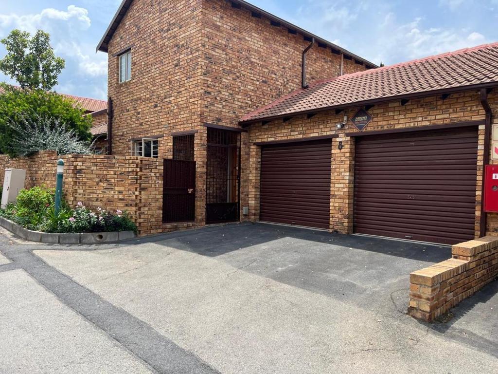 ein Backsteingebäude mit zwei Garagentüren darauf in der Unterkunft Pelistay in Sundowner in Boskruin