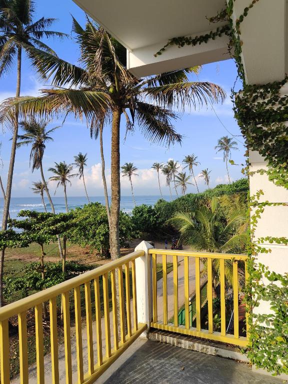 balcón con vistas a la playa y a las palmeras en The Sun Set, en Weligama