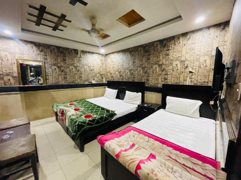 una camera con due letti e una parete di Hotel The Shalimar a Lahore