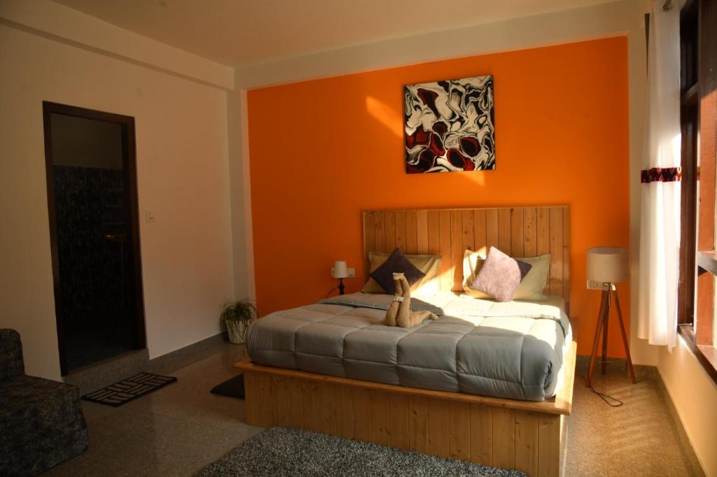 ein Schlafzimmer mit einem Bett mit einer orangefarbenen Wand in der Unterkunft Himtrek Stays Katagala in Kasol