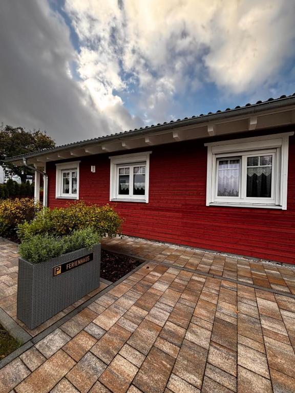 a red house with white windows and a brick driveway at Ferienhaus Fichtelwichtel in Mehlmeisel