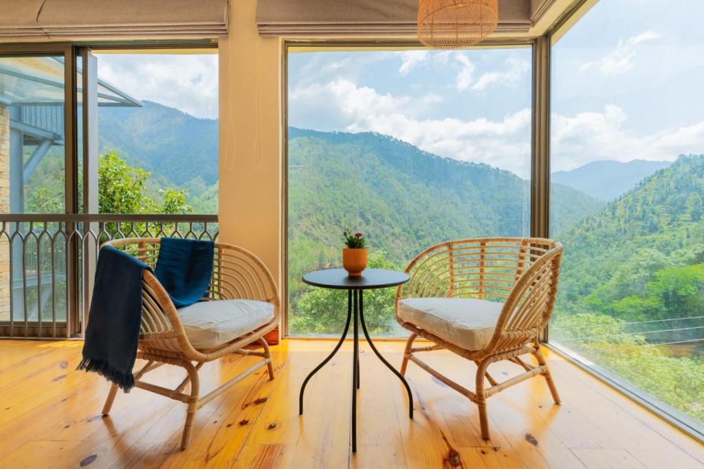 a room with two chairs and a table in front of windows at Over The World in Rāmgarh