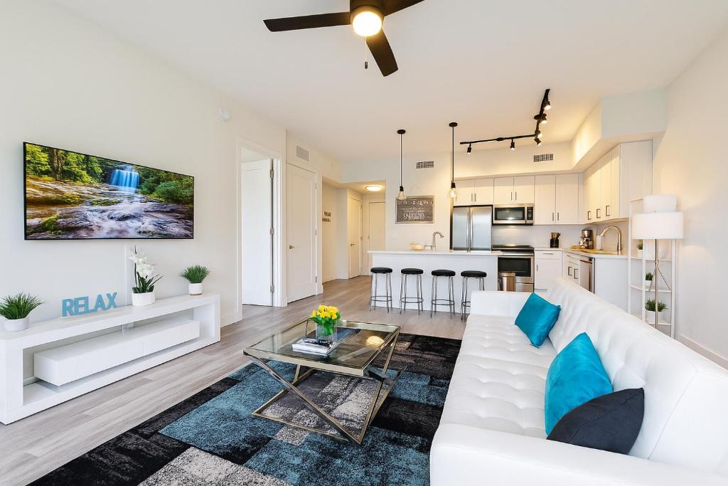 a living room with a white couch and a kitchen at Lux place and cozy 3Beds 2Rooms enjoy life in WPB Gym, EV Station Nearby the downtown and beaches in West Palm Beach