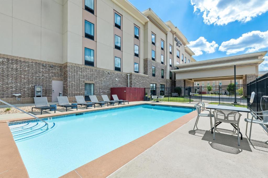 a swimming pool with chairs and a table in front of a building at Hampton Inn Texarkana in Texarkana