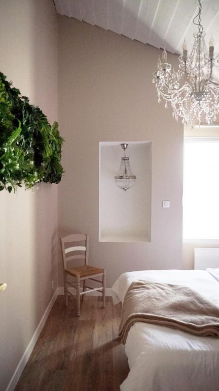 a bedroom with a bed and a chair and a chandelier at Le Chai des Poilanes in Liré