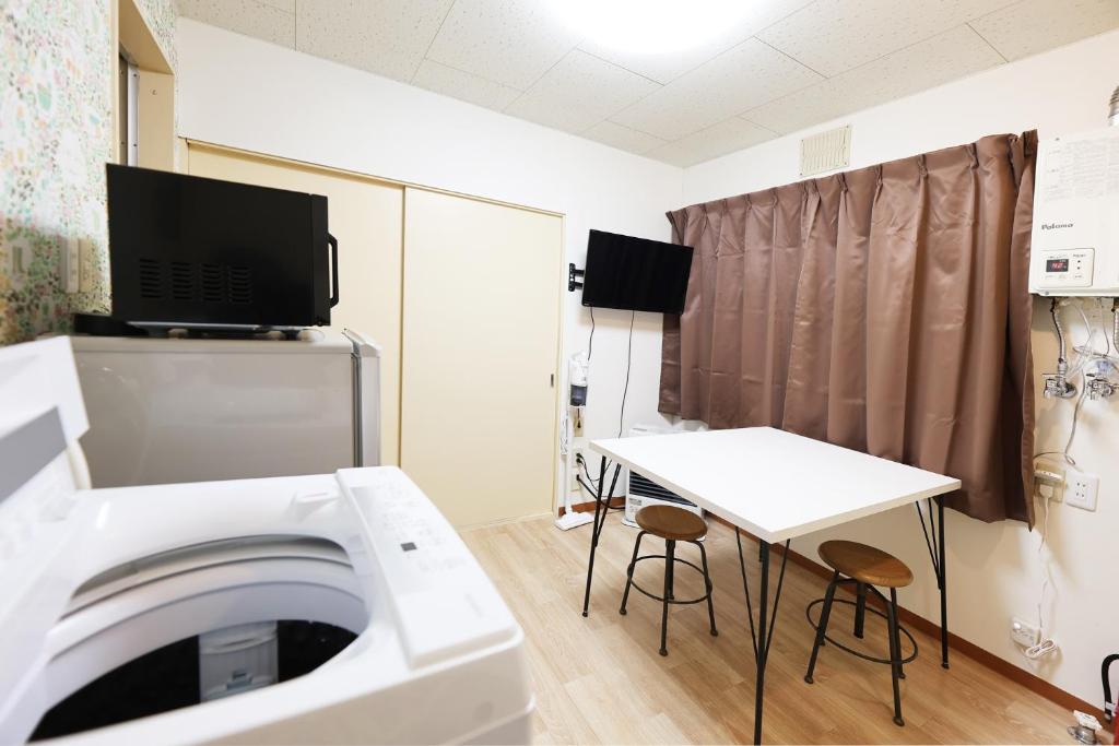Habitación con lavadora y mesa. en Vivere103ー札幌市地下鉄南平岸駅徒歩3分ーS-beds2, en Wada