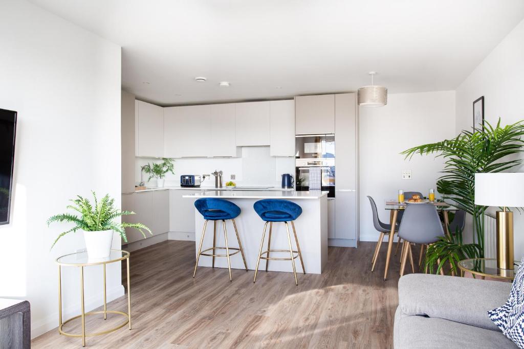 a kitchen and living room with white cabinets and blue stools at Stylish 2-Bed Penthouse Sleeps 6 Central Location in Belfast