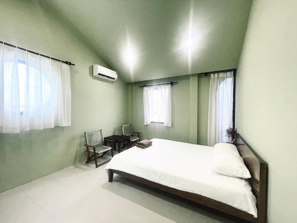 a bedroom with a white bed and a green wall at Biển house in Ấp Khánh Phước (1)
