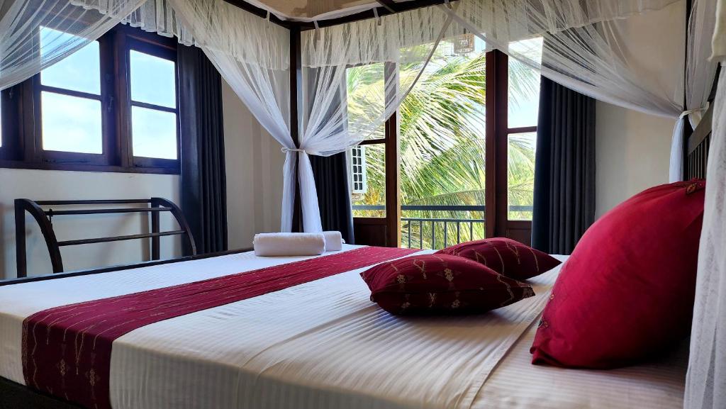 een slaapkamer met een bed met rode kussens en een raam bij MobyDick House in Mirissa