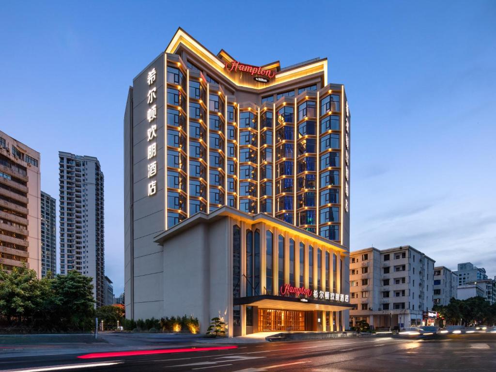 a tall building with lights on it in a city at 海口国贸希尔顿欢朋酒店 in Haikou