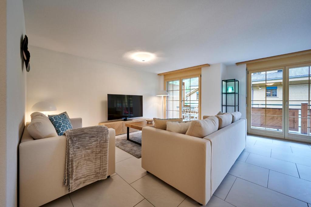 a living room with two couches and a tv at Great Location, Spacious, nice views, modern in Lauterbrunnen