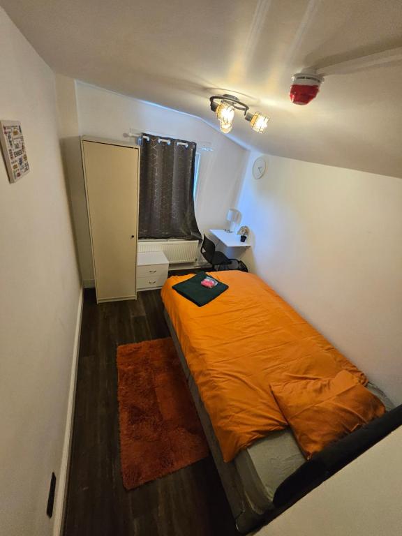 ロンドンにあるSky homesのオレンジ色のベッドが置かれた小さな寝室