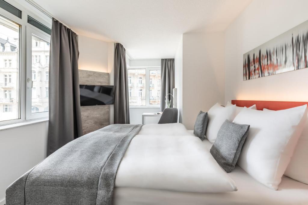 a hotel room with a large bed with white pillows at Garner Hotel Wiesbaden City by IHG in Wiesbaden