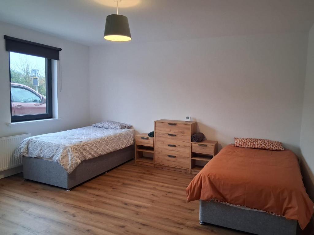 a bedroom with two beds and a dresser and a window at Railway House, Halfway in Ballinhassig