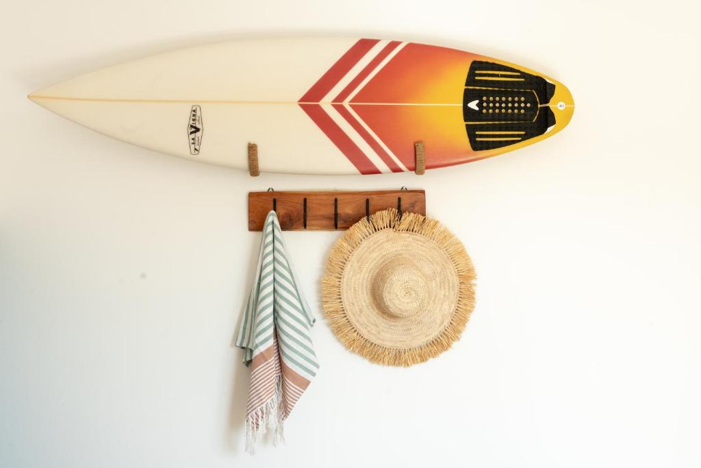 a surfboard and a hat hanging on a wall at Alma Ventura House - Majanicho in Majanicho