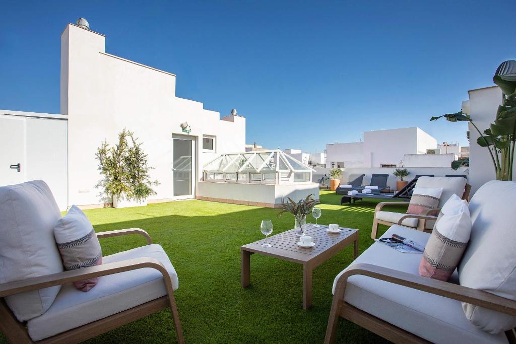 eine Terrasse mit Stühlen und einem Tisch auf dem Rasen in der Unterkunft Genteel Home Patrocinio Cádiz in Cádiz