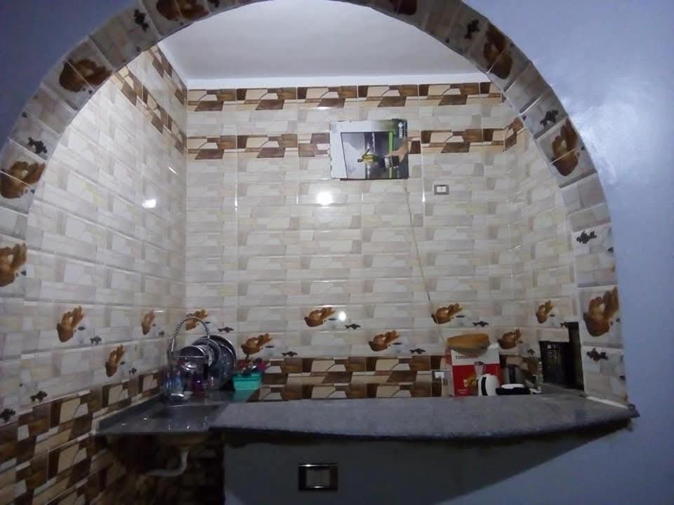 een keuken met een stenen muur met een boog bij Nubian house in Jazīrat Salūjah