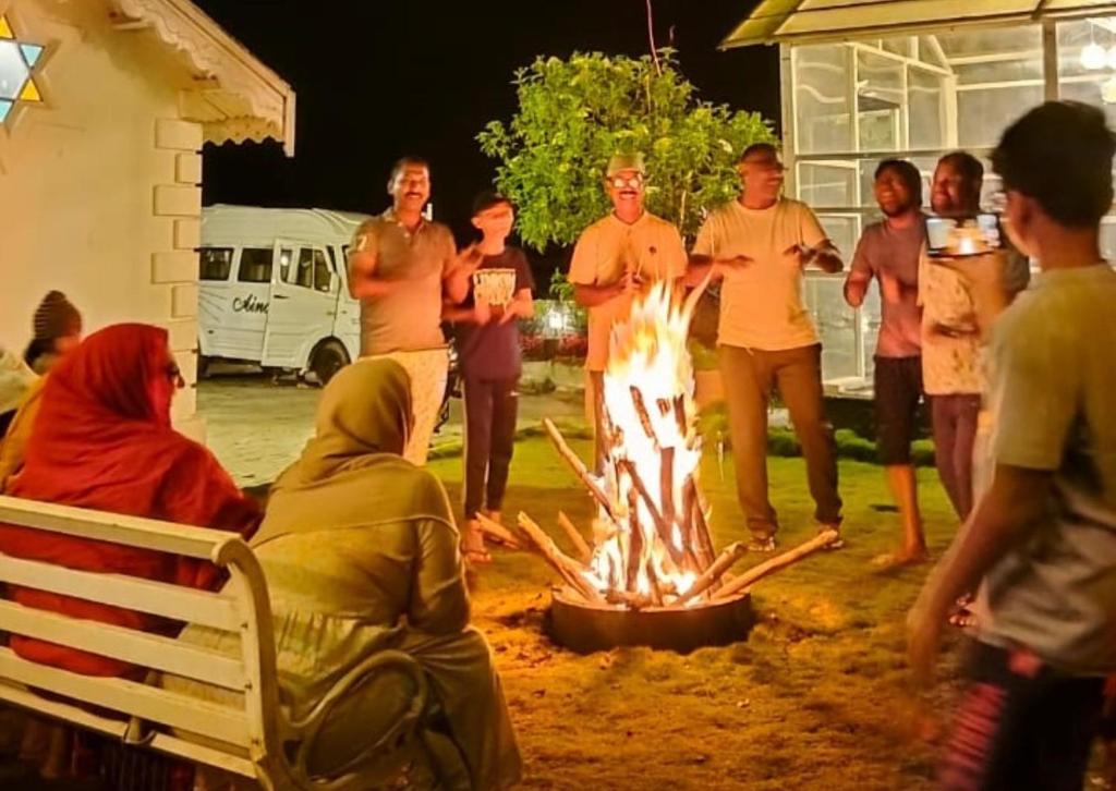 a group of people standing around a fire at Hidden heritage ins in Ooty