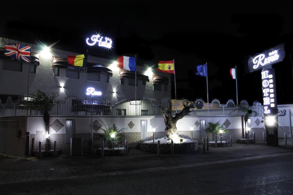 a hotel at night with flags and neon signs at Hotel Runa in Mugnano di Napoli