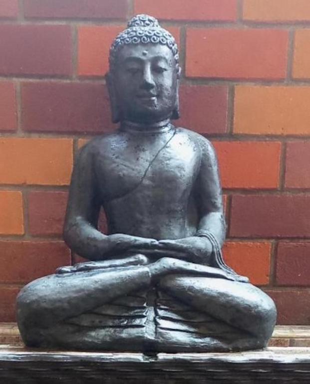 a statue of a man sitting in front of a brick wall at ZEN MOON Hostel in Yogyakarta