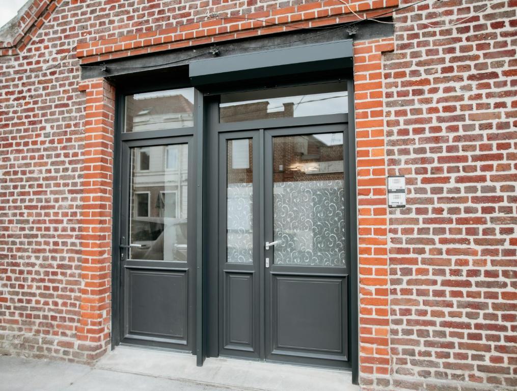 a black door on a brick building at Studio tout Équipé in Cambrai
