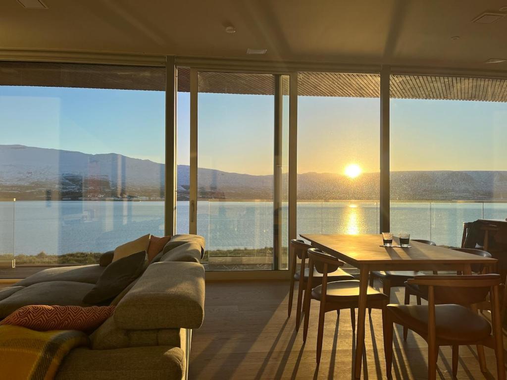 een woonkamer met een bank en een tafel met uitzicht bij Saeluheimur - Oceanside Sanctuary in Akureyri