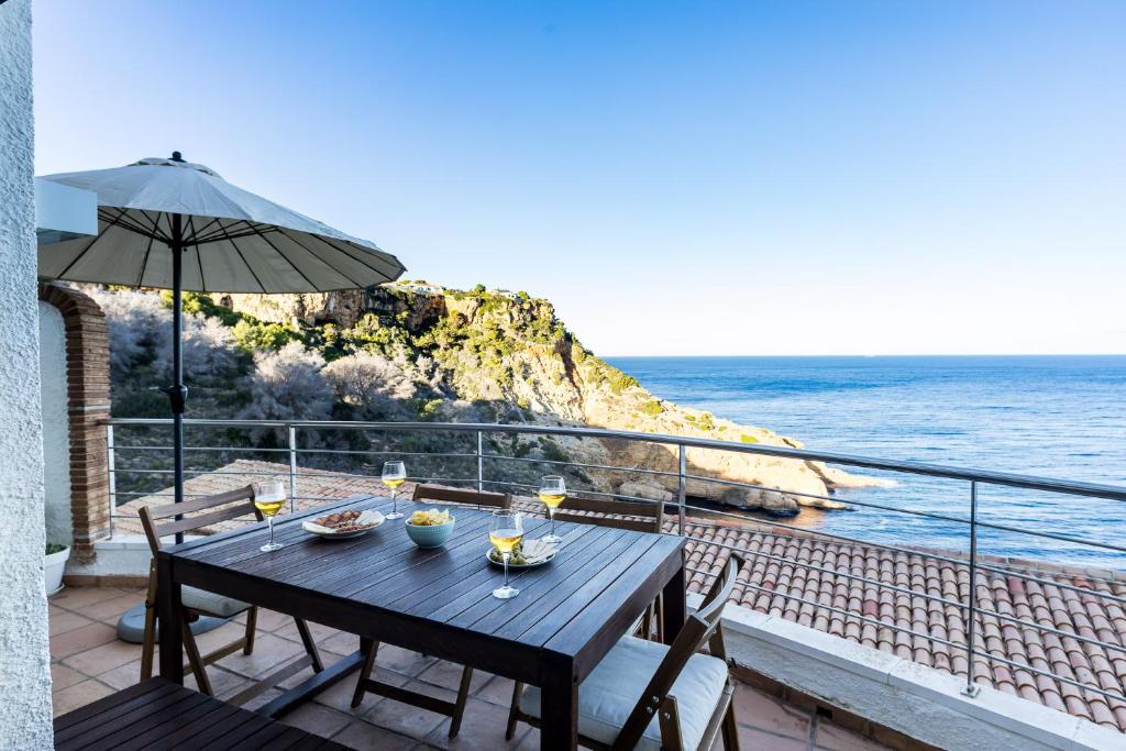 a table with chairs and an umbrella and the ocean at Moonkey - Casa El Cabo in Balcon del Mar