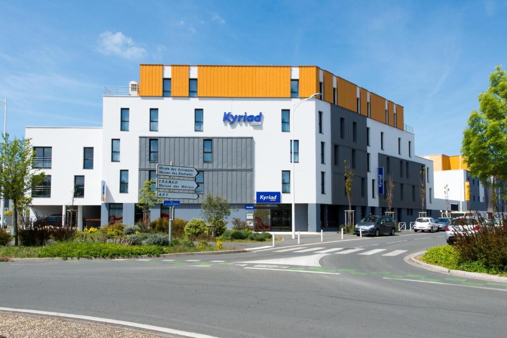 a large white building on a street with a road at Kyriad La Rochelle Centre - Les Minimes in La Rochelle