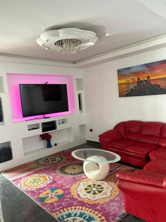 a living room with a red couch and a flat screen tv at casa di mac dakar in Dakar