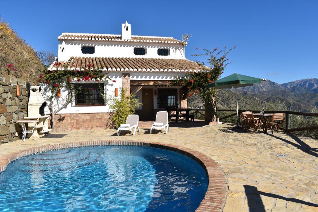 a villa with a swimming pool in front of a house at Finca Lagarillo with private Pool in Cómpeta