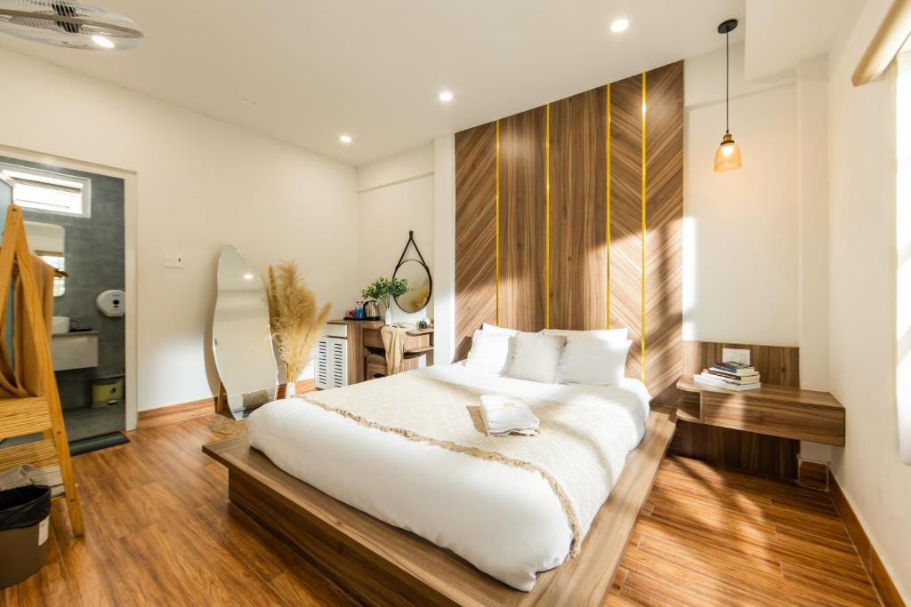 a bedroom with a large white bed and wooden floors at The Morris Central Hotel - O'TEL in Da Lat