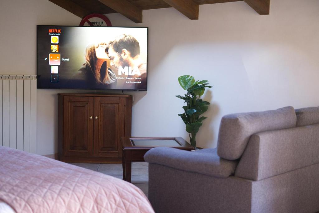 ein Wohnzimmer mit einer Couch und einem Fernseher an der Wand in der Unterkunft Loft 1855 'centro cittá' in Domodossola