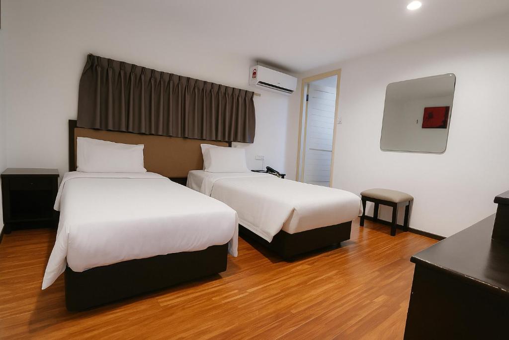 two beds in a hotel room with wooden floors at Watermelon Hotel in Miri
