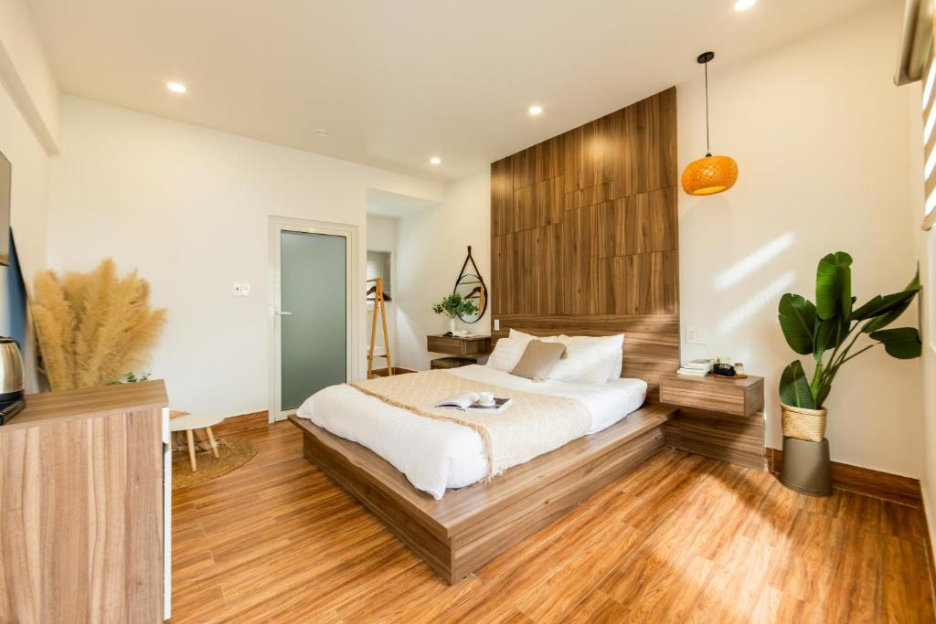 a bedroom with a large bed and wooden floors at The Morris Central Hotel - O'TEL in Da Lat