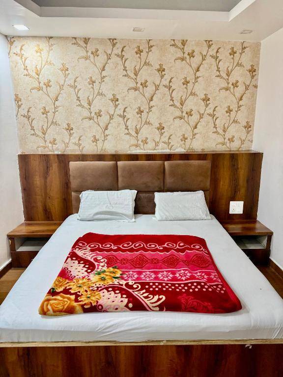 a bed with a red blanket on top of it at Moti Mahal Delux in Bahādurgarh