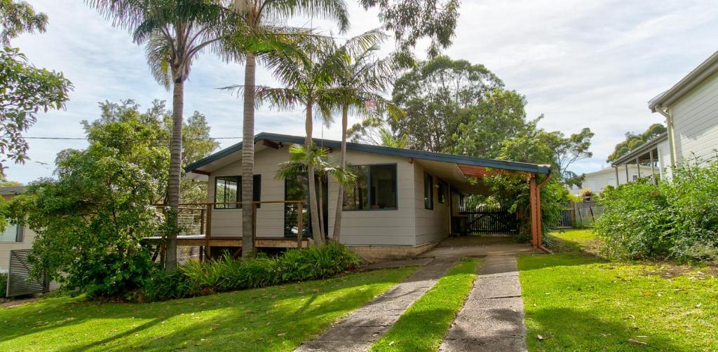 a house with palm trees in the yard at Lockhart Leafy Cottage - walk to Mollymook Beach in Mollymook