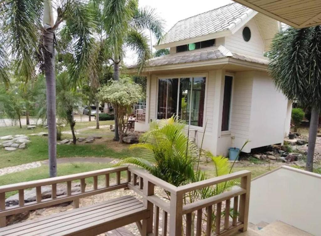 un porche avec un banc en bois devant une maison dans l'établissement ขวัญใจปราณ รีสอร์ท, à Ban Pak Nam Pran