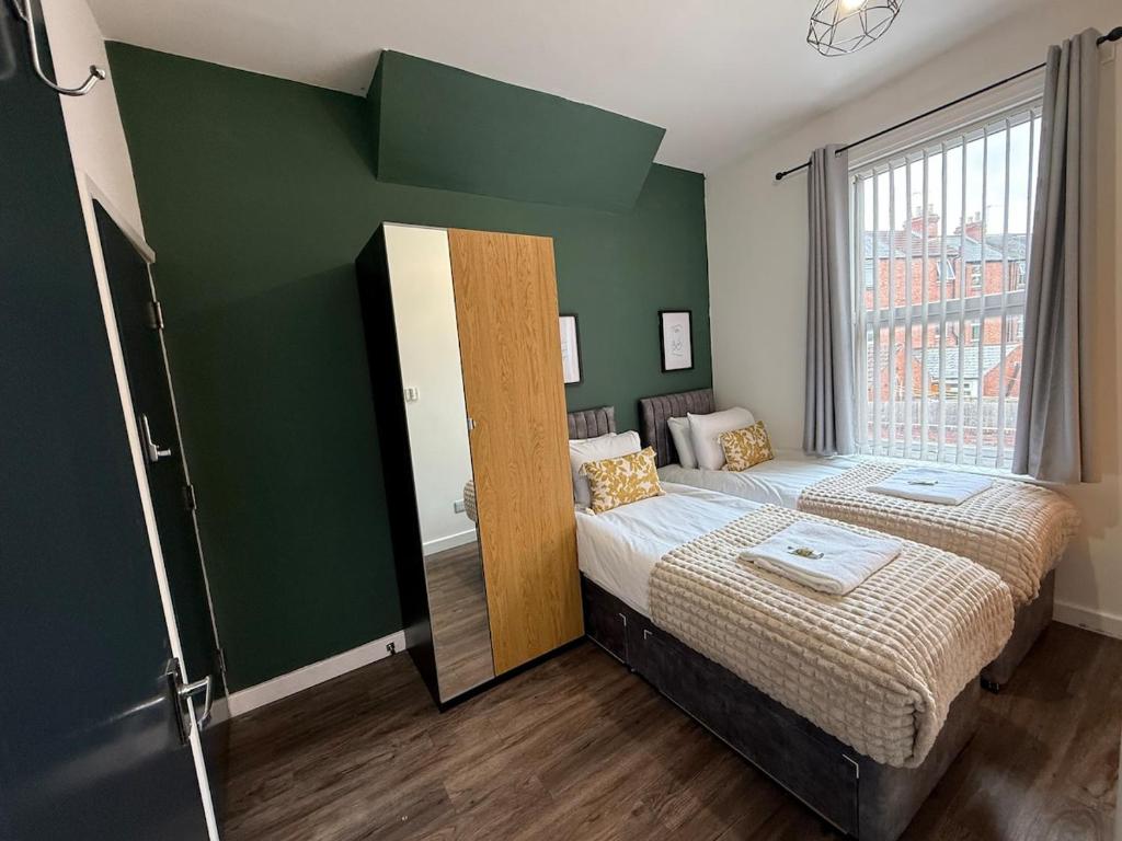 a bedroom with two beds and a green wall at Modern & Spacious, 4BR 4Bath, Parking, Sleeps 8 in Coventry