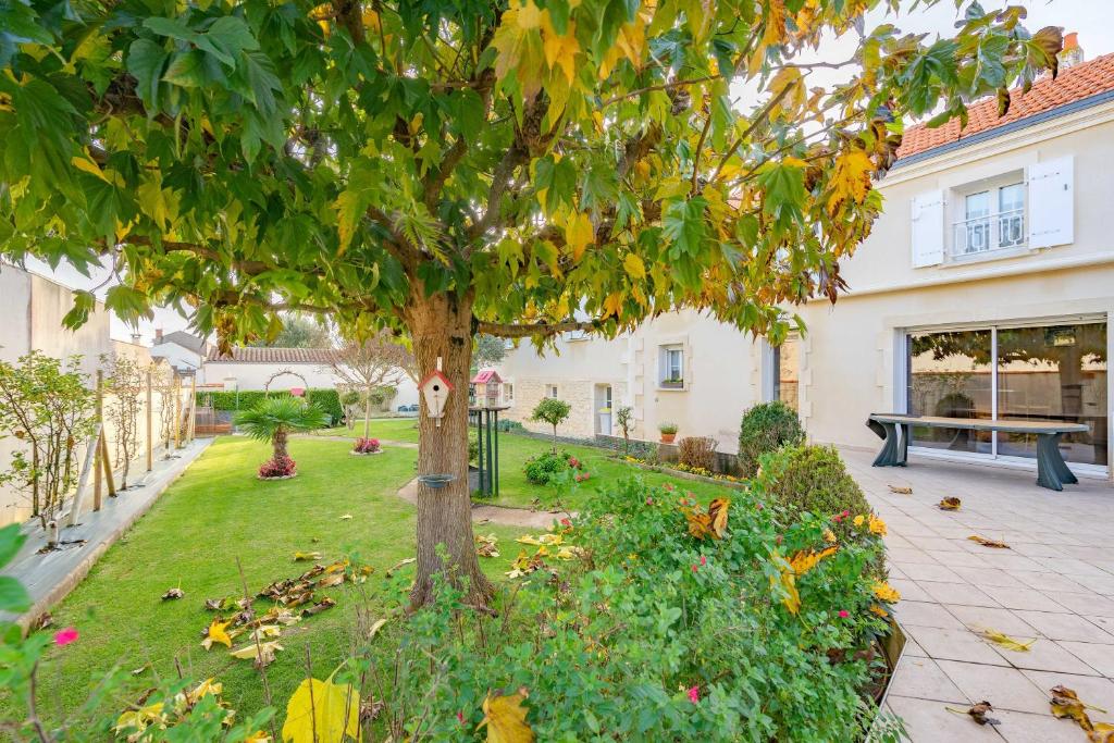 a tree in the middle of a yard with a bench at Au Paradis Des Hotes - Chambre Ile in Fouras