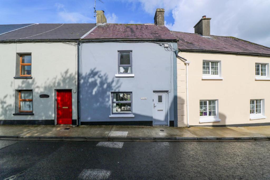 ein weißes Haus mit einer roten Tür auf einer Straße in der Unterkunft Rose Cottage in Killala