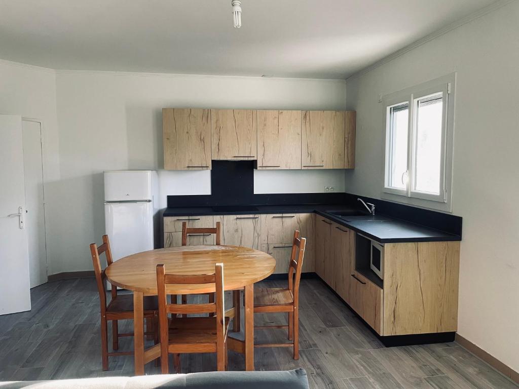 eine Küche mit einem Holztisch und Stühlen darin in der Unterkunft Appartement fonctionnel in Malleval