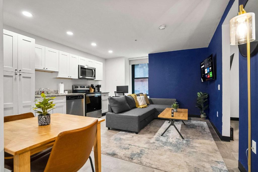 CozySuites Stunning 1BR in Downtown Pitts #03 في بيتسبرغ: مطبخ وغرفة معيشة مع أريكة وطاولة