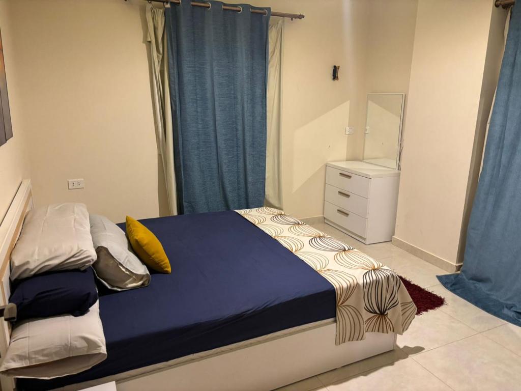 a bedroom with a bed with blue curtains and a dresser at Quiet HOME in Hurghada