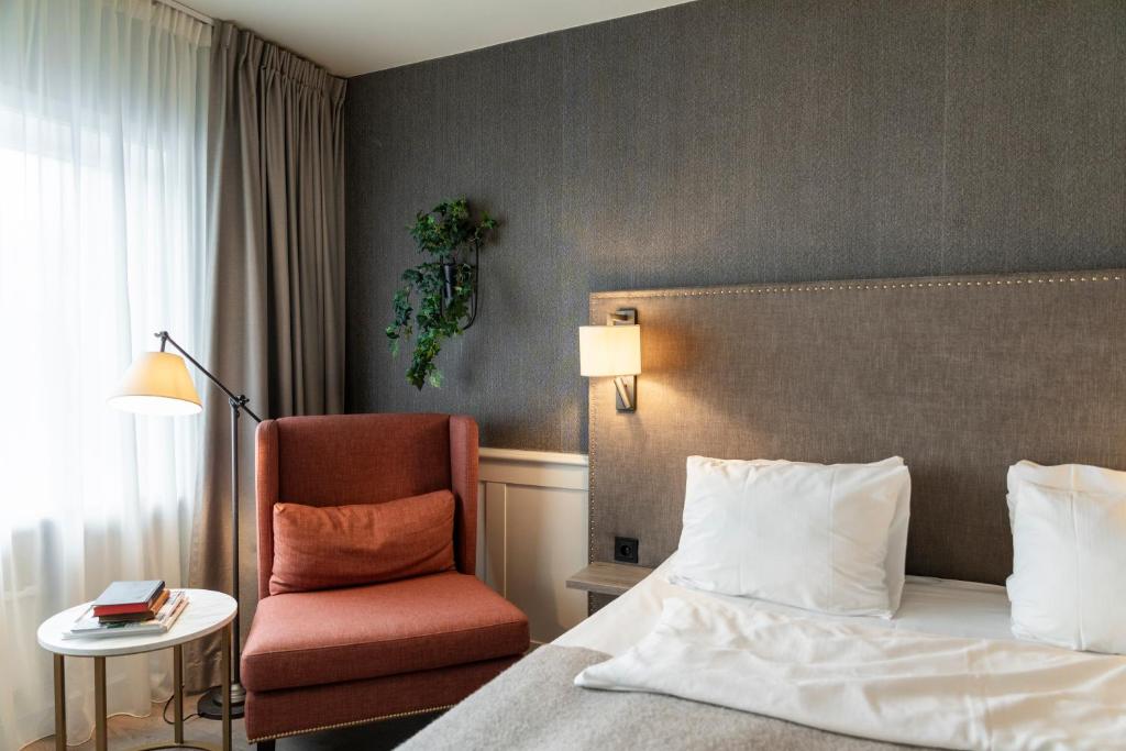 a hotel room with a bed and a chair at Home Hotel Grand Bodø in Bodø