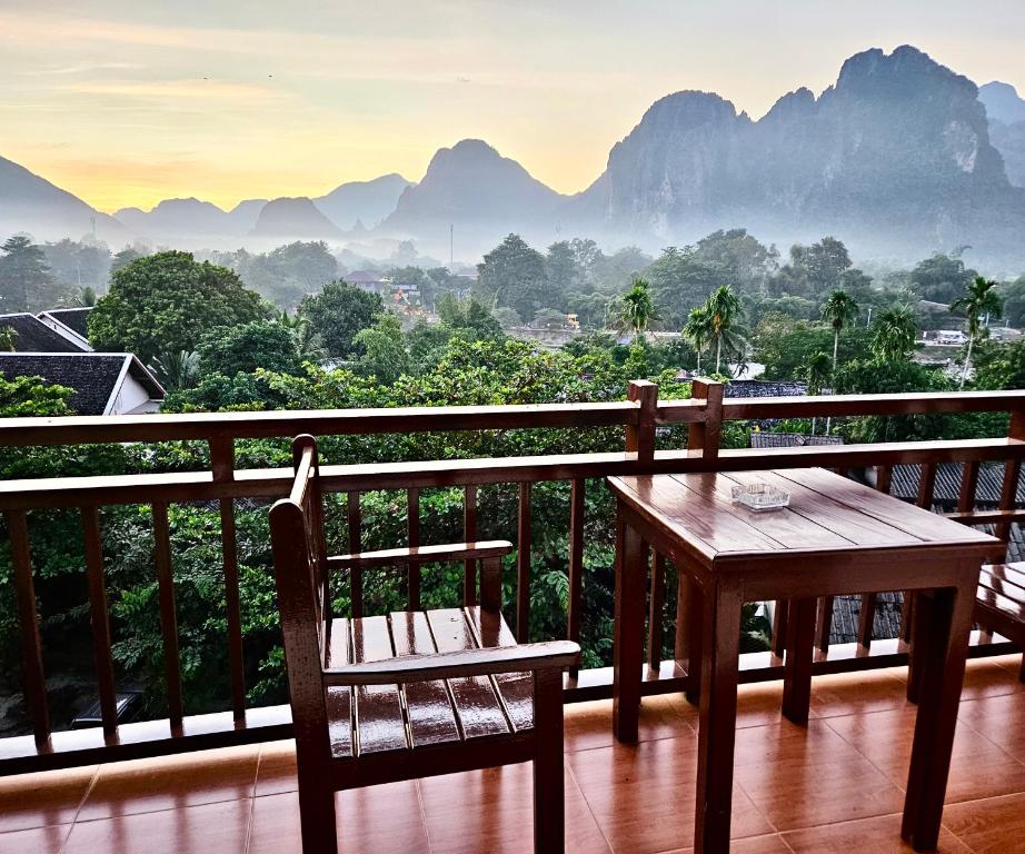 een tafel en stoelen op een balkon met uitzicht op de bergen bij west water hostel in Vang Vieng