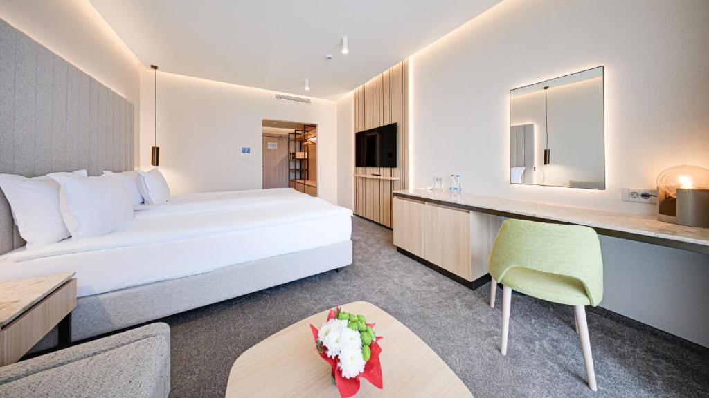 a hotel room with a large white bed and a table at Hotel Complex SamElyon in Samokov
