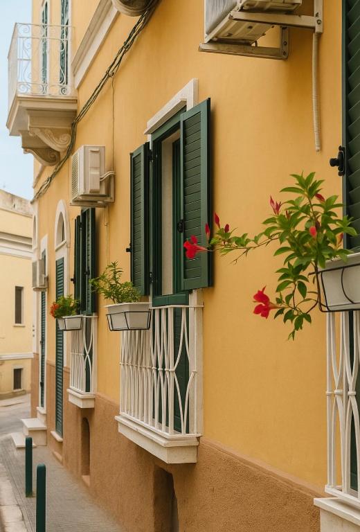 a building with green shutters and flowers on balconies at DIMORA ELIVA in Monopoli