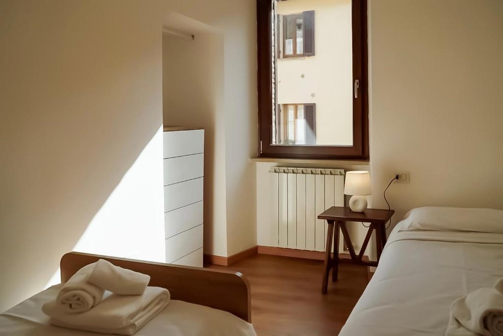 a bedroom with two beds and a mirror and a window at GUBBIO LIVING - by Angeloni in Gubbio