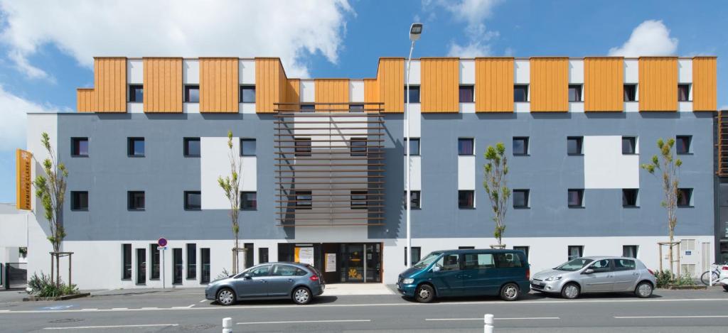 un edificio con coches estacionados frente a él en Première Classe La Rochelle Centre - Les Minimes en La Rochelle